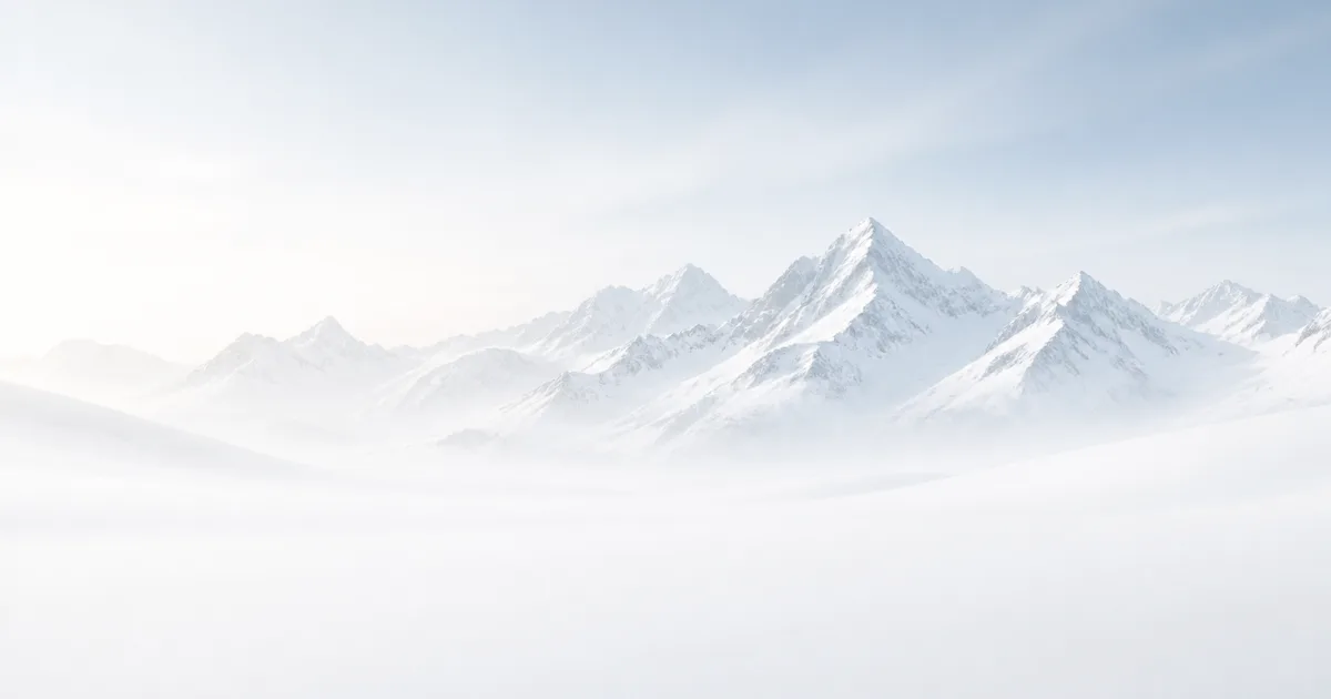 Panorama di cime alpine innevate in una foschia chiara